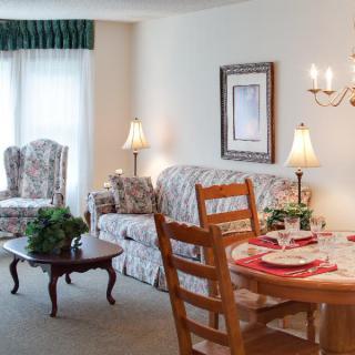 A cozy interior with a living room and dining area featuring classic furniture and warm lighting.