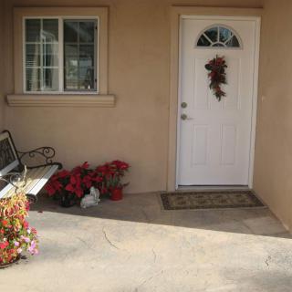 A cozy front porch with a white door adorned with seasonal decor, a bench, and potted plants.