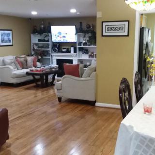 A cozy living room with a dining area featuring hardwood floors, sofas, and a television.