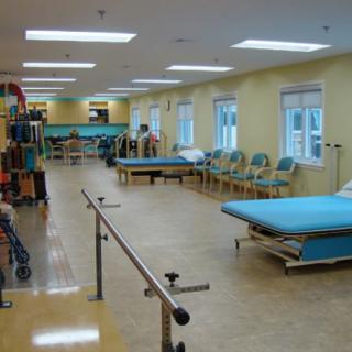 A spacious rehabilitation center with therapy equipment and treatment beds.
