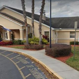 Front view of a building entrance with landscaping and palm trees.
