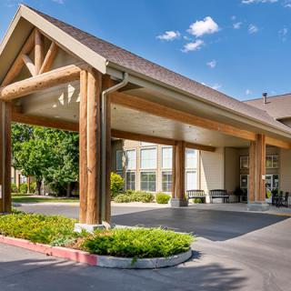 A hotel entrance with a wooden frame and a covered driveway surrounded by greenery.