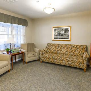 A cozy living room with a patterned sofa, two armchairs, and a window allowing natural light in.