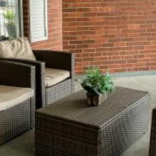 A cozy outdoor patio setup with wicker furniture and a potted plant.