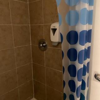 A bathroom shower with a blue polka dot curtain and tile walls.