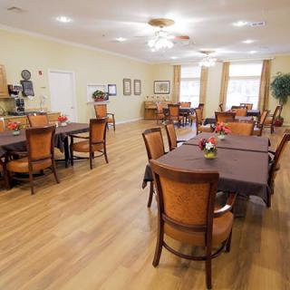A well-lit dining room with several tables and chairs arranged neatly.