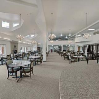 A spacious dining hall with elegant chandeliers and neatly arranged tables and chairs.