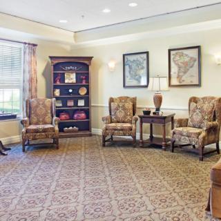 A cozy lobby with traditional decor, featuring armchairs and a bookshelf.
