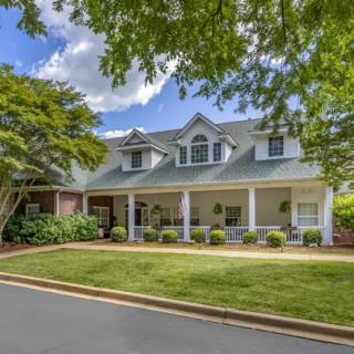 A charming suburban house with a well-maintained lawn and surrounding trees.