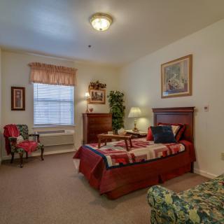 A cozy bedroom with a bed, chair, and decorative elements.