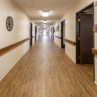 A well-lit corridor featuring wooden laminate flooring and multiple doors along the sides.