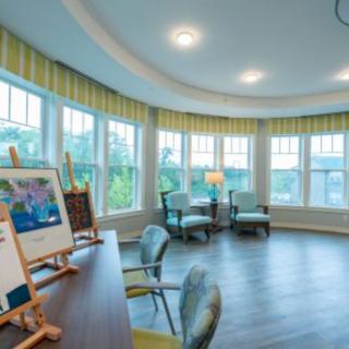 A bright art room with large windows, featuring easels and comfortable seating.
