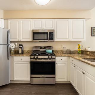 A modern kitchen with white cabinets and stainless steel appliances.