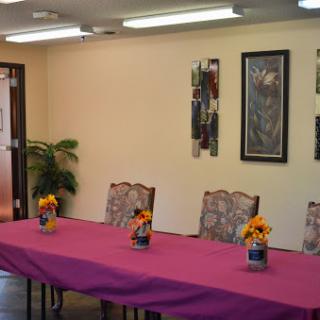 A well-arranged meeting room featuring a pink tablecloth, decorative flowers, and stylish furniture.
