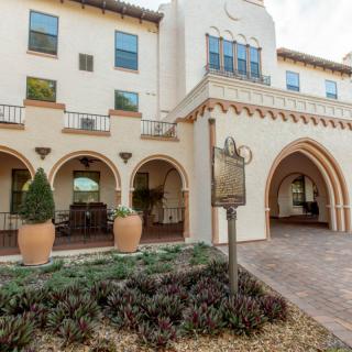 A historic building with arched entrances and decorative plants at the entrance.