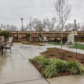 A well-maintained outdoor patio area with garden furniture, a walkway, and landscaping.
