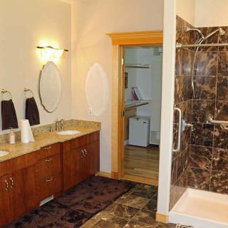 A modern bathroom featuring a double sink vanity and a marble-tiled shower.
