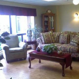 A cozy living room setup featuring a floral sofa, an armchair, and a wooden coffee table adorned with plants.