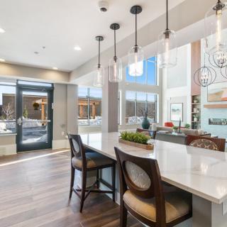 A modern kitchen and dining area featuring sleek countertops, pendant lighting, and stylish bar stools.