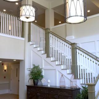 A modern interior featuring a staircase with elegant chandeliers and white railings.