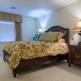 A cozy bedroom with a large bed, wooden nightstand, and decorative lamp.