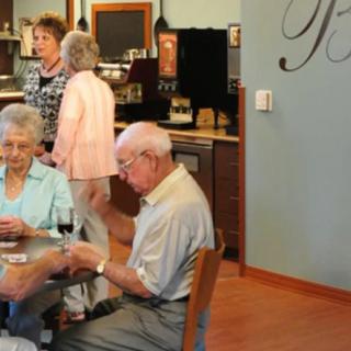 A group of seniors playing cards and socializing in a cafe setting.
