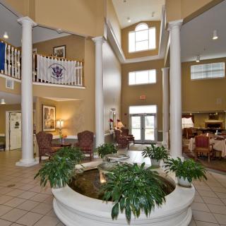 A spacious and elegant hotel lobby with tall columns, a central plant display, and comfortable seating areas.