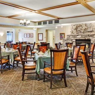 A cozy dining room with elegantly set tables and a stone fireplace.