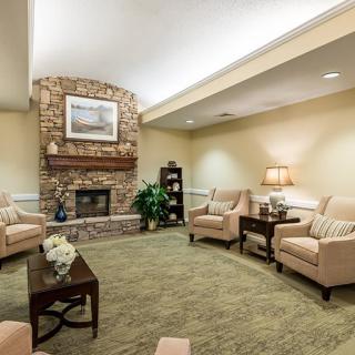 A cozy living room with a stone fireplace, comfortable seating, and warm lighting.