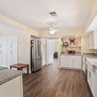 A modern kitchen with white cabinets, stainless steel appliances, and wood flooring.