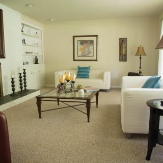A cozy living room with white sofas, a glass coffee table, and tasteful decorations.