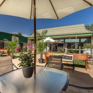 A sunny outdoor seating area with an umbrella and potted plants, perfect for relaxation.