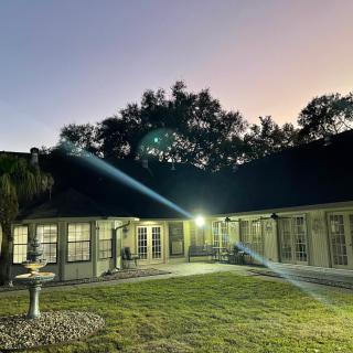 A serene evening view of a house with exterior lights illuminating the yard.