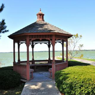 A picturesque gazebo overlooking a serene lake, surrounded by lush greenery.
