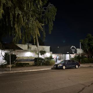 A quiet street at night with a parked car in front of a residential house.