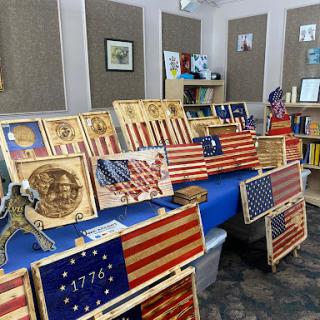 A display of intricately crafted wooden pieces featuring various American flags and historical symbols.