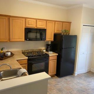 A modern kitchen with wooden cabinets, black appliances, and a tiled floor.