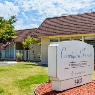 A residential building with a lawn and a prominent sign reading 'Courtyard Terrace' under a clear sky.
