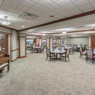 An elegant dining area with neatly arranged tables and chairs, featuring a carpeted floor and soft lighting.