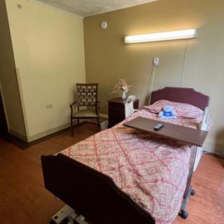 A simple hospital room with a single bed and basic furnishings.