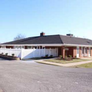 A single-story residential building with a sloped roof and a front yard.