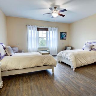 A spacious bedroom with two double beds, featuring a ceiling fan and large window.