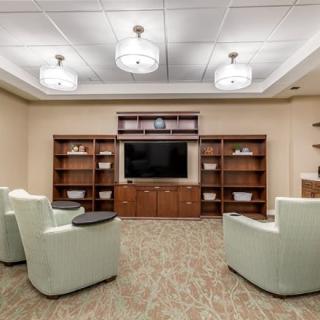 A cozy living room with armchairs facing a large television and surrounded by bookshelves.