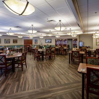 An empty restaurant dining area with neatly arranged tables and chairs under elegant lighting.