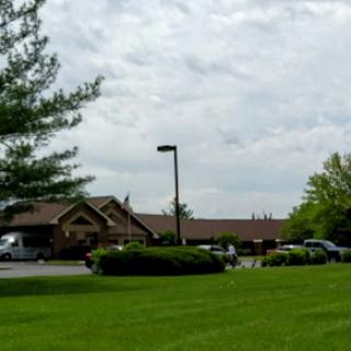A peaceful view of a building surrounded by greenery and a cloudy sky.