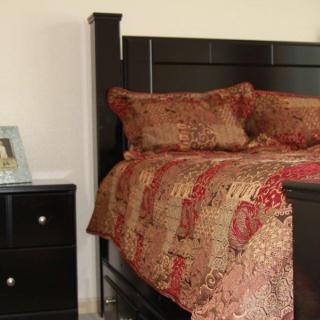 A cozy bedroom featuring a dark wooden bed with patterned bedding and a matching nightstand.