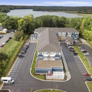 Aerial view of an apartment complex with a parking lot and a lake in the background.