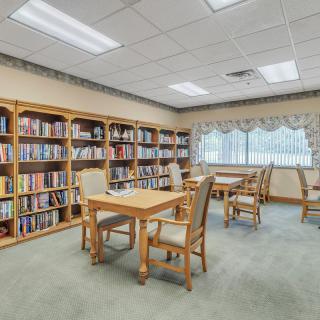 A quiet library room with bookshelves, tables, and chairs.