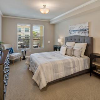 A modern, well-decorated bedroom with a large window and comfortable furnishings.