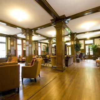 A spacious lounge area with wooden beams, comfortable seating, and large windows.